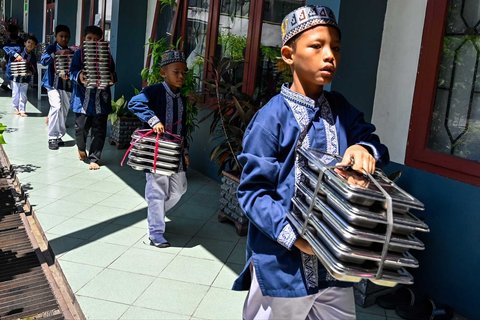Sejumlah siswa  membawa nampan Makanan Bergizi Gratis (MBG) di Sekolah Dasar Negeri 20 Banda Aceh, Aceh, Kamis (30/10/2025).