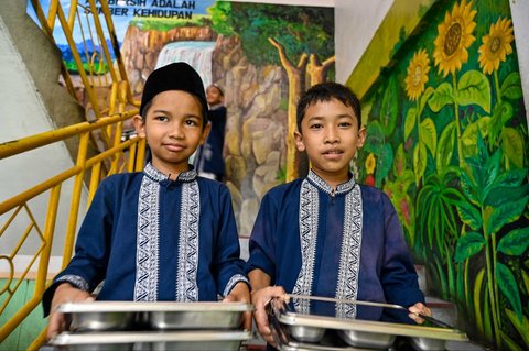 Siswa membawa nampan Makanan Bergizi Gratis (MBG) di Sekolah Dasar Negeri 20 Banda Aceh, Aceh, Kamis (30/10/2025).