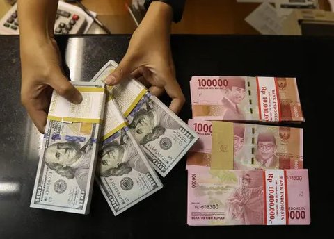 Karyawan menunjukkan uang dolar AS dan rupiah di Jakarta, Rabu (30/12/2020). Nilai tukar rupiah di pasar spot ditutup menguat 80 poin atau 0,57 persen ke level Rp 14.050 per dolar AS. (Liputa