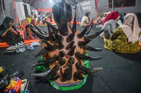 Seorang pria menjalani terapi bekam menggunakan tanduk sapi, yang disediakan oleh para relawan di tenda sementara yang didirikan untuk menampung keluarga santri yang hilang di Rumah Sakit Bhayangkara, Surabaya, Minggu (05/10/2025) malam.