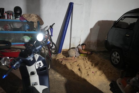 Warga berbaring di atas pasir dalam garasi di rumahnya r di Desa Legung Timur, Sumenep, Pulau Madura, Indonesia, Selasa (09/09/2025).