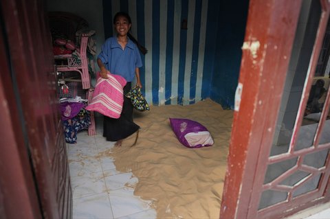 Warga memegang bantal di dalam kamar tidur yang berisi pasir untuk tidur warga, di Desa Legung Timur, Sumenep, Pulau Madura, Indonesia, Selasa (09/09/2025).