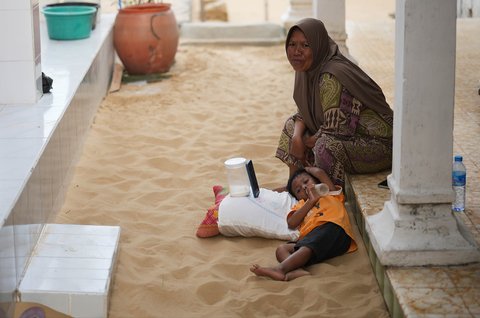 Seorang anak   terbaring di atas kasur pasir di kamar tidurnya di Desa Legung Timur, Sumenep, Pulau Madura, Indonesia, Selasa, (09/09/2025).
