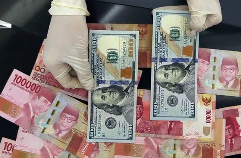 Karyawan menunjukkan uang dolar AS dan rupiah di Jakarta, Rabu (30/12/2020). Nilai tukar rupiah di pasar spot ditutup menguat 80 poin atau 0,57 persen ke level Rp 14.050 per dolar AS. (Liputa