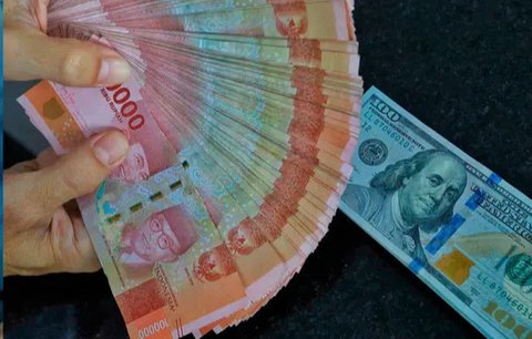 Karyawan menunjukkan uang dolar AS dan rupiah di Jakarta, Rabu (30/12/2020). Nilai tukar rupiah di pasar spot ditutup menguat 80 poin atau 0,57 persen ke level Rp 14.050 per dolar AS. (Liputa