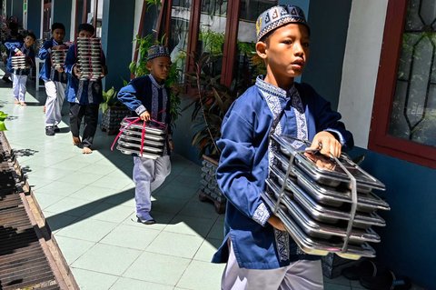 Sejumlah siswa  membawa nampan Makanan Bergizi Gratis (MBG) di Sekolah Dasar Negeri 20 Banda Aceh, Aceh, Kamis (30/10/2025).