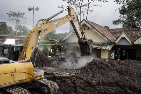Alat berat membersihkan abu di depan sebuah rumah yang hancur akibat aliran piroklastik Gunung Semeru di Desa Supiturang, Lumajang, Jawa Timur, Jumat (21/11/2025).