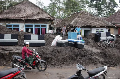 Warga menyelamatkan barang-barang dari sebuah rumah yang hancur akibat aliran piroklastik Gunung Semeru di Desa Supiturang, Lumajang, Jawa Timur, Jumat (21/11/2025).
