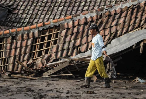 Warga menyelamatkan barang-barang dari sebuah rumah yang hancur akibat aliran piroklastik Gunung Semeru di Desa Supiturang, Lumajang, Jawa Timur, Jumat (21/11/2025).