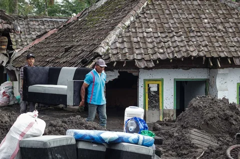 Warga menyelamatkan barang-barang dari sebuah rumah yang hancur akibat aliran piroklastik Gunung Semeru di Desa Supiturang, Lumajang, Jawa Timur, Jumat (21/11/2025).