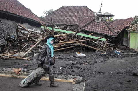 Warga menyelamatkan barang-barang dari sebuah rumah yang hancur akibat aliran piroklastik Gunung Semeru di Desa Supiturang, Lumajang, Jawa Timur, Jumat (21/11/2025).