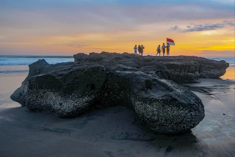 Pengunjung membuat konten media sosial saat senja di  Pantai Pasut di Tabanan, Bali
