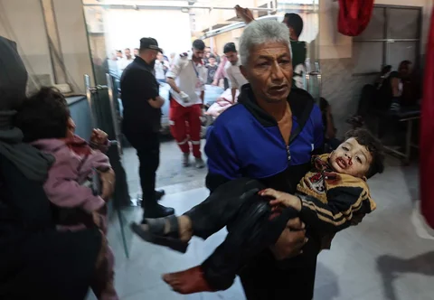 Warga menggendong seorang anak yang terluka setelah  serangan udara Israel di Rumah Sakit Al-Awda di Jalur Gaza tengah, Sabtu (22/11/2025).