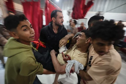Warga menggendong korban terluka setelah  serangan udara Israel di Rumah Sakit Al-Awda di Jalur Gaza tengah, Sabtu (22/11/2025).