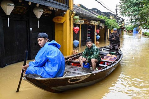 Orang-orang menyusuri jalan yang terendam banjir dengan perahu setelah hujan deras di Hoi An, Vietnam, Kamis 30 Oktober 2025. Sedikitnya sembilan orang tewas dan lima lainnya masih dinyatakan