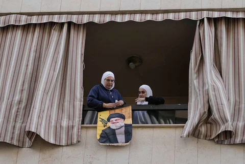 Warga menggantung foto mendiang pemimpin Hizbullah, Hassan Nasrallah pada sebuag Gedung yang rusak akibat serangan udara Israel Hareit Hreik, Beirut, Lebanon, Senin (2411/2025).