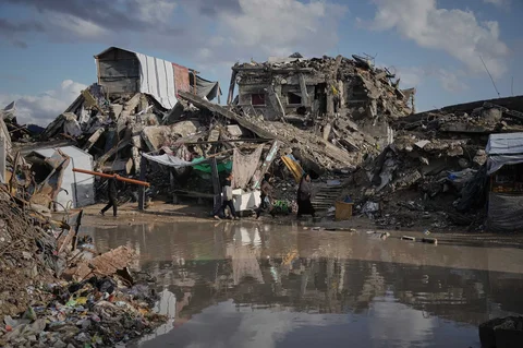 Warga Palestina berjalan diantara reruntuhan bangunan yang hancur  dengan kondisi banjir di utara Kota Gaza, Selasa, (25/11/2025).