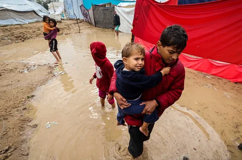 Anak-anak berjalan menlitasi banjir  di kamp pengungsi Maghazi di Jalur Gaza tengah, Selasa, (25/11/2025).