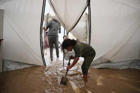 Anak-anak membersihkan air dari tenda keluarganya yang terendam banjir di kamp sementara untuk warga Palestina di Deir al-Balah, Jalur Gaza tengah, Selasa, (25/11/2025).
