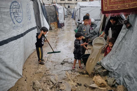 Warga Palestina membersihkan air dari tenda mereka yang terendam banjir di kamp sementara setelah hujan deras di Kota Gaza, Selasa, (25/11/2025).