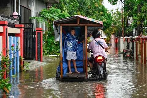 Kendaraan bermotor  melewati banjir di jalan yang tergenang setelah hujan deras di permukiman Darul Imarah, pinggiran Banda Aceh, Kamis (27/11/2025).