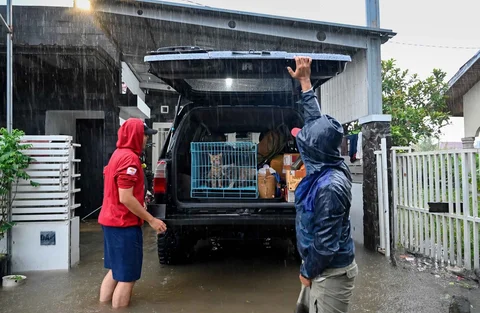 Warga menyelamatakan hewan peliharaannya di kawasan perumahan yang tergenang banjir di permukiman Darul Imarah, pinggiran Banda Aceh, Kamis (27/11/2025).