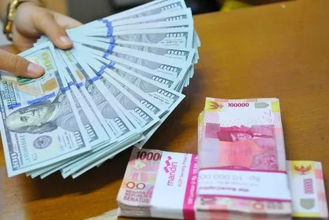 Petugas menunjukkan mata uang dolar dan mata uang rupiah di penukaran uang di Jakarta, Rabu (9/11). Nilai tukar rupiah terhadap dolar Amerika Serikat (AS) pada saat jeda siang ini kian terpur