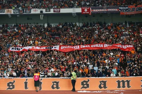 Suporter Persija membawa spanduk bertulisakan Indonesia Emas Bukan Indonesia Bekas, dalam mendukung pemerintah memberantas import pakaian bekas saat Laga pekan ke-14 BRI Super League