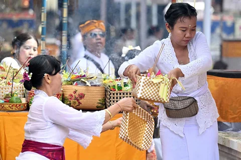 Seorang perempuan Hindu Bali menerima persembahan selama perayaan keagamaan Kuningan di Pulau Serangan, Bali, Sabtu (29/11/2025).