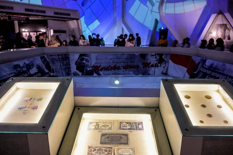 Perangko lama Indonesia dan uang kertas Jepang ditampilkan saat pengunjung menyaksikan video imersif Pertempuran Surabaya dalam acara Malam di Museum 2025 di Museum 10 November, Surabaya, Sabtu (29/11/2025) malam.