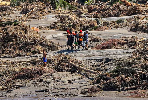 Petugas penyelamat berjalan melewati puing-puing saat mengevakuasi seorang warga desa yang sakit untuk dibawa ke rumah sakit terdekat di Bireuen, Provinsi Aceh, Sabtu (29/11/2025).