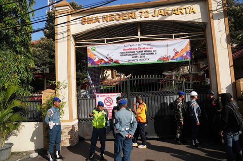 Petugas polisi dan personel militer berjaga di gerbang pintu masuk SMAN 72 Jakarta, Jumat (07/11/2025).