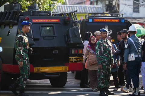 Petugas polisi dan personel militer berjaga di sekitar pintu masuk SMAN 72 Jakarta, Jumat (07/11/2025).