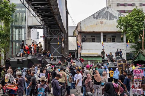 Warga berfoto dengan kendaraan militer selama Pekan Raya Marinir Indonesia di Jalan Gubernur Suryo, Surabaya, Jawa Timur, Minggu (9/11/2025).