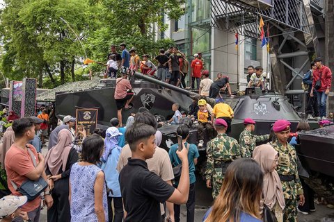 Warga berfoto dengan kendaraan militer selama Pekan Raya Marinir Indonesia di Jalan Gubernur Suryo, Surabaya, Jawa Timur, Minggu (9/11/2025).