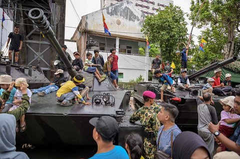 Warga berfoto dengan kendaraan militer selama Pekan Raya Marinir Indonesia di Jalan Gubernur Suryo, Surabaya, Jawa Timur, Minggu (9/11/2025).
