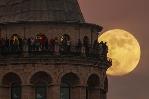 Bulan purnama terakhir tahun ini yang dikenal sebagai Cold Moon terbit melalui langit cerah melewati serangkaian lampu putih di corniche Doha, di Doha, Qatar, Rabu (7/12/2022). Bulan purnama