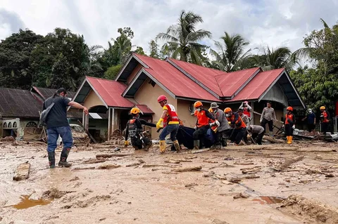 Tim penyelamat membawa jenazah korban banjir di Agam, Sumatera Barat, Indonesia, Minggu, (30/11/2025).