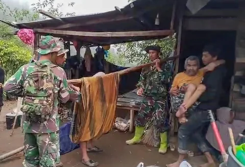 Anggota Koramil 05/Permata TNI AD mengevakuasi sepasang lansia dari wilayah terisolir menuju Puskesmas Buntul di Gucci Desa Burni Pase, Kecamatan Permata, Kabupaten Bener Meriah, Kamis (11/12/2025).