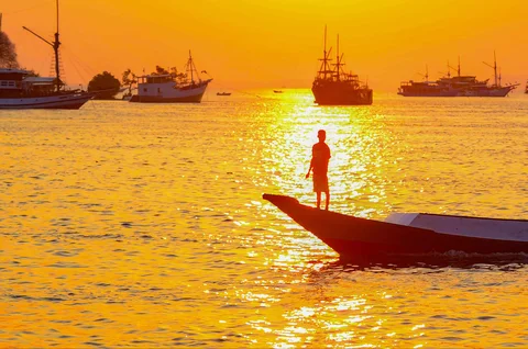 Nelayan dengan perahunya  melintasi matahari terbenam di Labuan Bajo, NTT