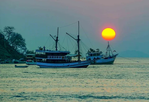 Kru kapal phinisi menyaksikan  matahari terbenam di Labuan Bajo, NTT