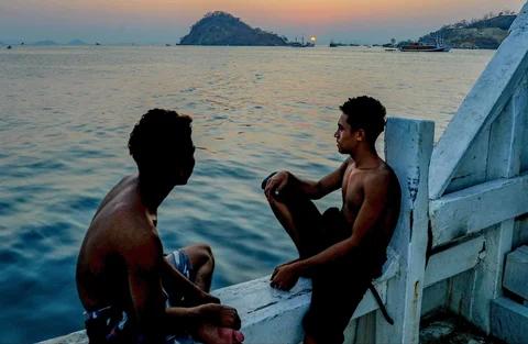 Kru kapal phinisi menyaksikan  matahari terbenam di Labuan Bajo, NTT