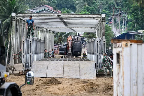 Prajurit TNI Kodam Iskandar Muda bersama petugas Kementerian Pekerjaan Umum menyelesaikan pembangunan jembatan bailey untuk memperbaiki sementara jembatan Juli yang rusak akibat bencana banjir bandang di Bireuen, Aceh, Minggu (14/12/2025),