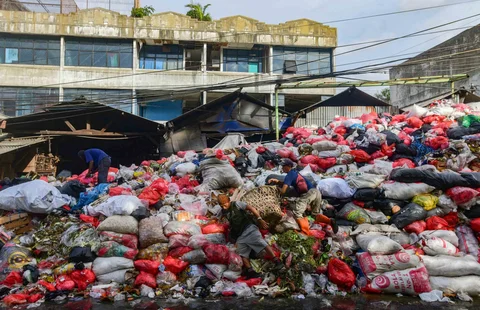 Petugas mengatur tumpukan sampah pada pinggir jalan di kawasan Pasar Manggis, Ciputat, Tangerang Selatan, Senin (15/12/2025).