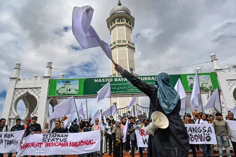 Massa dari berbagai elemen yang tergaabung dalam Aksi Koalisi Masyarakat Sipil Aceh melakukan aksi unjuk rasa di depan Masjid Raya Baiturrahman, Banda Aceh, Kamis (18/12/2025).