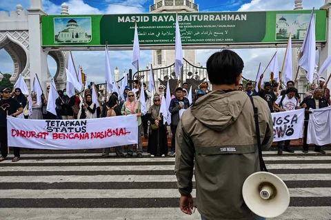 Massa dari berbagai elemen yang tergaabung dalam Aksi Koalisi Masyarakat Sipil Aceh melakukan aksi unjuk rasa di depan Masjid Raya Baiturrahman, Banda Aceh, Kamis (18/12/2025).