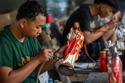 Seorang pekerja menyelesaikan pembuatan patung keagamaan Kristen di bengkel kerajinan Studio Malta Jaya di Bantul, Yogyakarta, Kamis (18/12/2025).