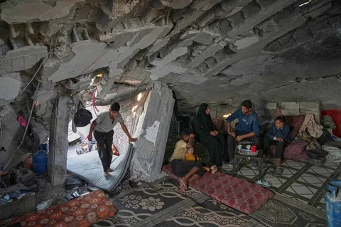 Sahar Taroush berbicara dengan saudara laki-lakinya di rumahnya yang sebagian runtuh di , Kota Gaza, Selasa (11/12/2025).