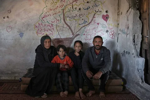 Amani dan Mohammed Halawa berpose untuk foto bersama anak-anak mereka, Aya, 13, dan Bashir, 10, di dalam rumah mereka yang sebagian runtuh di  Kota Gaza, Selasa,  (25/11/2025).