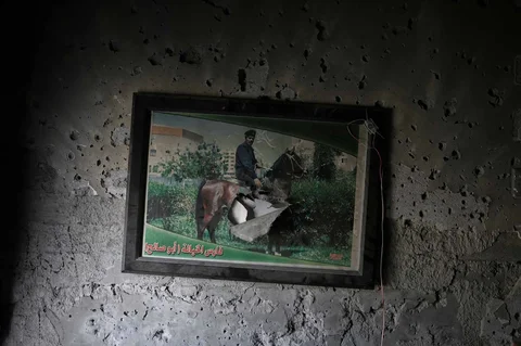 Sebuah foto berbingkai Muhammad Qutay yang bertugas di dinas keamanan Otoritas Palestina tergantung di dinding yang rusak di rumah keluarga di  Kota Gaza, Rabu (25/11/2025).